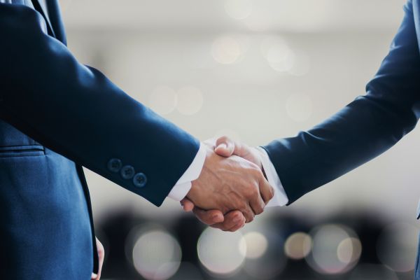 Business professionals shaking hands in an office setting.
